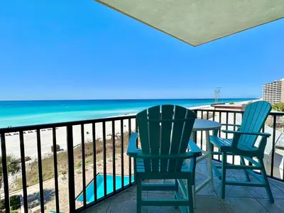two chairs and a table on a balcony with the beach at Pelican Walk 510 in Panama City Beach