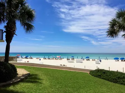a beach with chairs and umbrellas and the ocean at Pelican Walk 510 in Panama City Beach