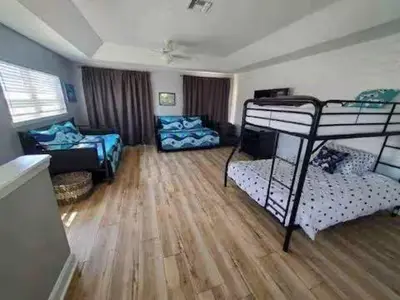 a room with two bunk beds and a living room at Coastal Castaway-Beach Retreat-Steps 2 Sand-Sleep 10-Pool-Hot tub in Panama City Beach