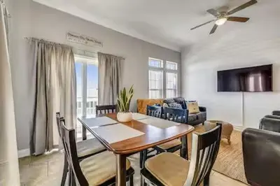 a dining room and living room with a table and chairs at Coastal Castaway-Beach Retreat-Steps 2 Sand-Sleep 10-Pool-Hot tub in Panama City Beach