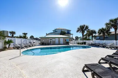 a swimming pool with chaise lounges and chairs at Coastal Castaway-Beach Retreat-Steps 2 Sand-Sleep 10-Pool-Hot tub in Panama City Beach