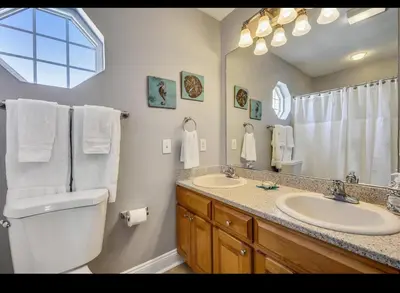 a bathroom with a toilet and two sinks and a mirror at Coastal Castaway-Beach Retreat-Steps 2 Sand-Sleep 10-Pool-Hot tub in Panama City Beach