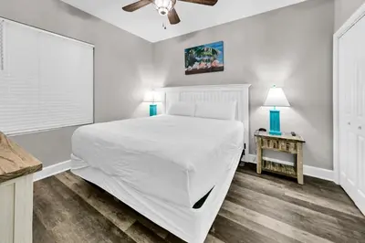 a bedroom with a large white bed and a table at Tidewater 1916 in Panama City Beach
