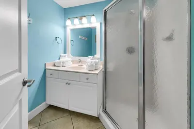 a bathroom with a sink and a shower with a mirror at Tidewater 1916 in Panama City Beach