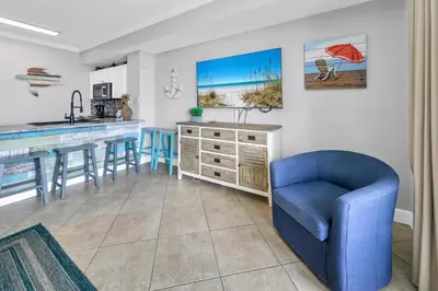 a kitchen with a blue chair and a kitchen island at Tidewater 1916 in Panama City Beach