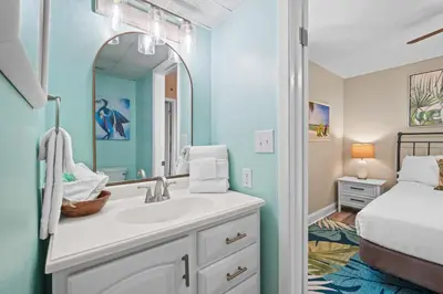 a bathroom with a sink and a mirror and a bed at Sunbird Beach Resort 1011W By Book That Condo in Panama City Beach