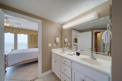 a bathroom with a sink and a bed and a mirror at Treasure Island 0901 in Panama City Beach