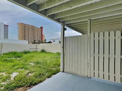 a wooden fence next to a field with buildings at PC Beach Retreat A in Panama City Beach