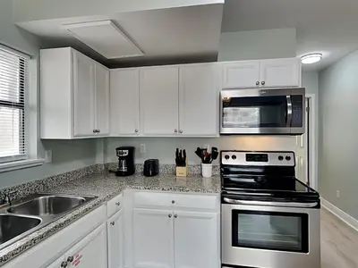 a kitchen with white cabinets and a stove and a sink at PC Beach Retreat A in Panama City Beach