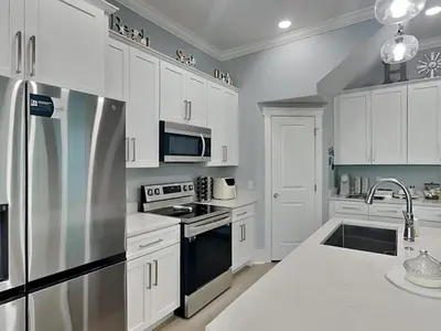 a kitchen with white cabinets and a stainless steel refrigerator at Ocean Pearl Villa in Panama City Beach