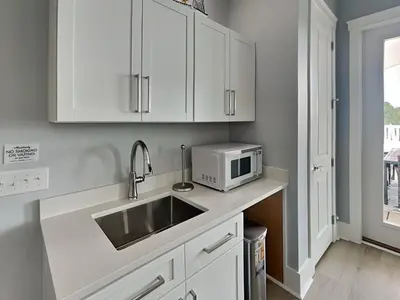 a kitchen with white cabinets and a sink and a microwave at Ocean Pearl Villa in Panama City Beach