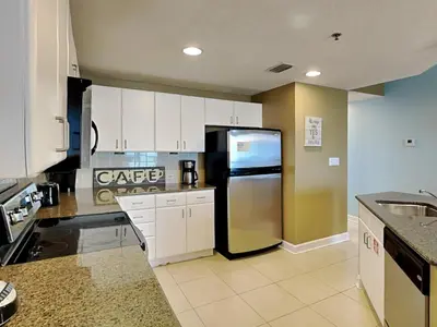 a kitchen with a stainless steel refrigerator and white cabinets at Grand Panama Beach Resort - The Grand II #803 in Panama City Beach