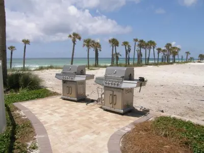 two picnic tables on the beach with palm trees at Grand Panama Beach Resort - The Grand II #803 in Panama City Beach