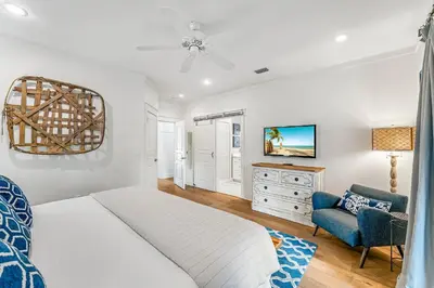 a bedroom with a white bed and a blue chair at No Ragrets in Inlet Beach