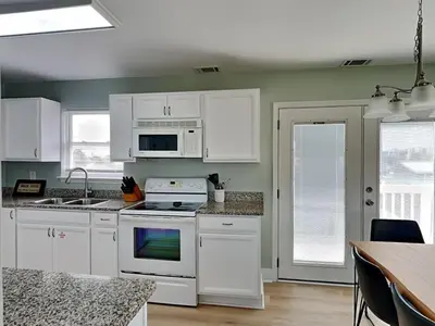 a kitchen with white cabinets and a stove top oven at PC Beach Retreat C in Panama City Beach