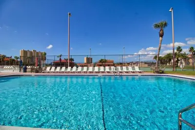 a large blue swimming pool with chairs and a palm tree at Renovated Townhome 5 mins walk to Beach, in the best resort in PCB, Horizon South in Panama City Beach