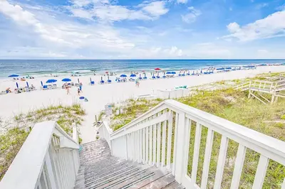 a staircase leading to a beach with people on it at Relax Awhile - Carriage House in Panama City Beach