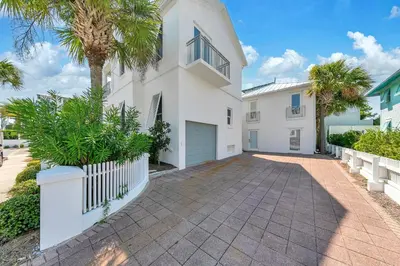 a white house with a palm tree and a driveway at Relax Awhile - Carriage House in Panama City Beach