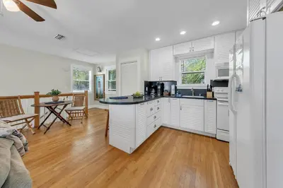 a kitchen with white cabinets and a table in a room at Relax Awhile - Carriage House in Panama City Beach