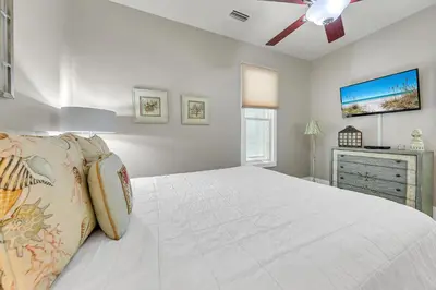 a white bedroom with a bed and a ceiling fan at Relax Awhile in Panama City Beach
