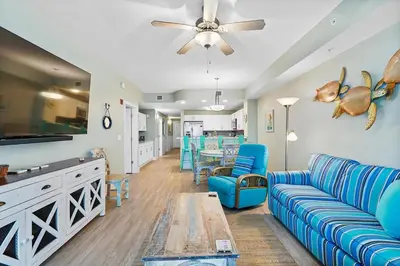 a living room with a blue couch and a table at Calypso 3-1011 in Panama City Beach