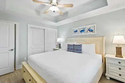 a bedroom with a white bed and a ceiling fan at Calypso 3-1011 in Panama City Beach
