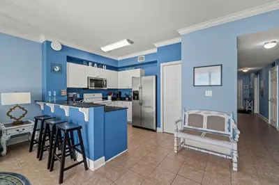 a kitchen with blue walls and bar stools at Stunning Beachfront Condo, Walk to Pier Park,Pools in Panama City Beach