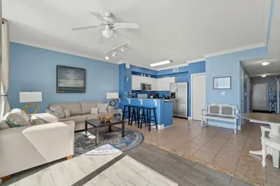 a living room with blue walls and a couch and a kitchen at Stunning Beachfront Condo, Walk to Pier Park,Pools in Panama City Beach