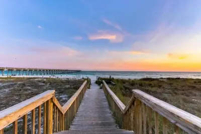 a wooden boardwalk to the beach at sunset at Stunning Beachfront Condo, Walk to Pier Park,Pools in Panama City Beach