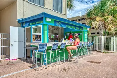 a woman sitting at a bar with chairs in front at Stunning Beachfront Condo, Walk to Pier Park,Pools in Panama City Beach