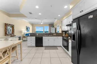 a kitchen with white cabinets and black appliances at Treasure Island #0309 in Panama City Beach