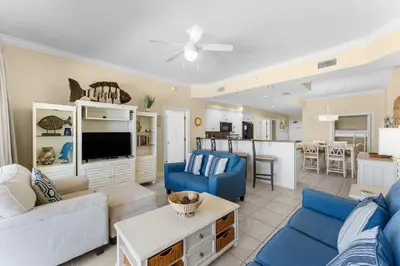a living room with blue couches and a kitchen at Treasure Island #0309 in Panama City Beach