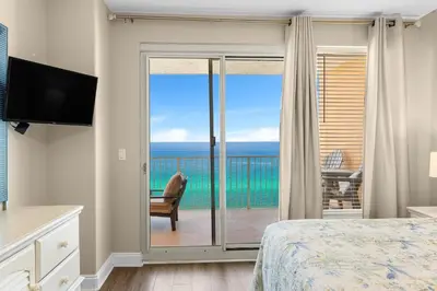 a bedroom with a sliding glass door with a view of the ocean at Treasure Island #0607 in Panama City Beach