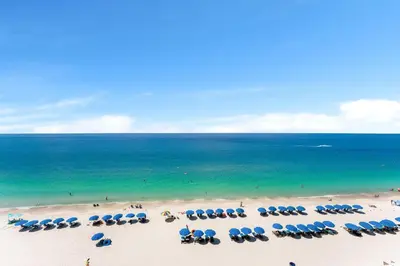 a beach with chairs and umbrellas and the ocean at Treasure Island #0607 in Panama City Beach