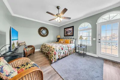 a bedroom with a bed and a tv and windows at Seaside Serenity in Panama City Beach