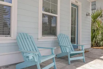 two blue chairs sitting on the front porch of a house at Southern Breeze - Private Pool - 100 Feet From The Beach! in Panama City Beach