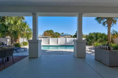 a patio with a swimming pool and palm trees at Luxury Breeze - Luxury Home With Private Pool & Private Beach! in Panama City Beach