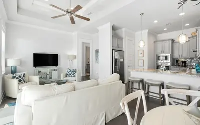 a living room with white furniture and a kitchen at 12 Milestone Dr C by Oversee 30A in Inlet Beach