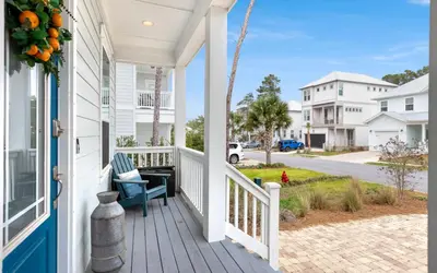 a porch with a blue chair on a white house at 310 Grande Pointe by Oversee 30A in Inlet Beach