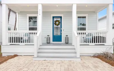 a white house with a blue door and stairs at 310 Grande Pointe by Oversee 30A in Inlet Beach