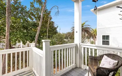 a wicker chair sits on the front porch of a white house at 310 Grande Pointe by Oversee 30A in Inlet Beach
