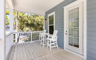 a porch with white chairs and a table on it at 91 San Juan by Oversee 30A in Santa Rosa Beach