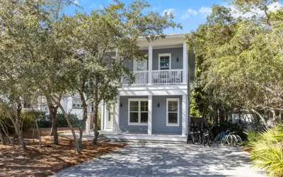 a white house with trees in front of it at 91 San Juan by Oversee 30A in Santa Rosa Beach