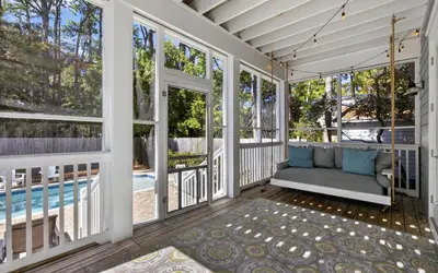 a porch with a swing and a pool at 91 San Juan by Oversee 30A in Santa Rosa Beach