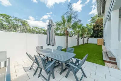 a patio with a table and chairs and a lawn at 94 Pinecrest by Oversee 30A in Inlet Beach