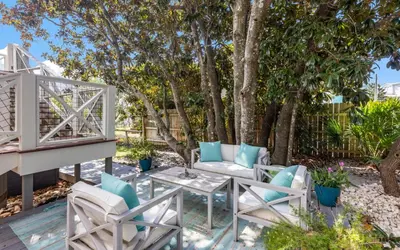 a patio with chairs and a table and trees at A Hasty Retreat by Oversee 30A in Seagrove Beach
