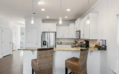 a kitchen with white cabinets and bar stools at After Dune Delight by Oversee 30A in Inlet Beach