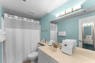 a bathroom with a sink and a toilet and a mirror at Shores of Panama Chic 2-BD Beachfront Resort Condo! by Dolce Vita Getaways! in Panama City Beach