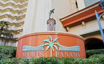 a sign in front of a building with a palm tree at Shores of Panama Chic 2-BD Beachfront Resort Condo! by Dolce Vita Getaways! in Panama City Beach