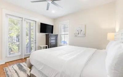 a white bedroom with a bed and a flat screen tv at Beach Dreamer by Oversee 30A in Seacrest